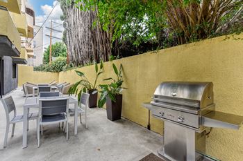 Outdoor BBQ area with gas grill and tables and chairs.